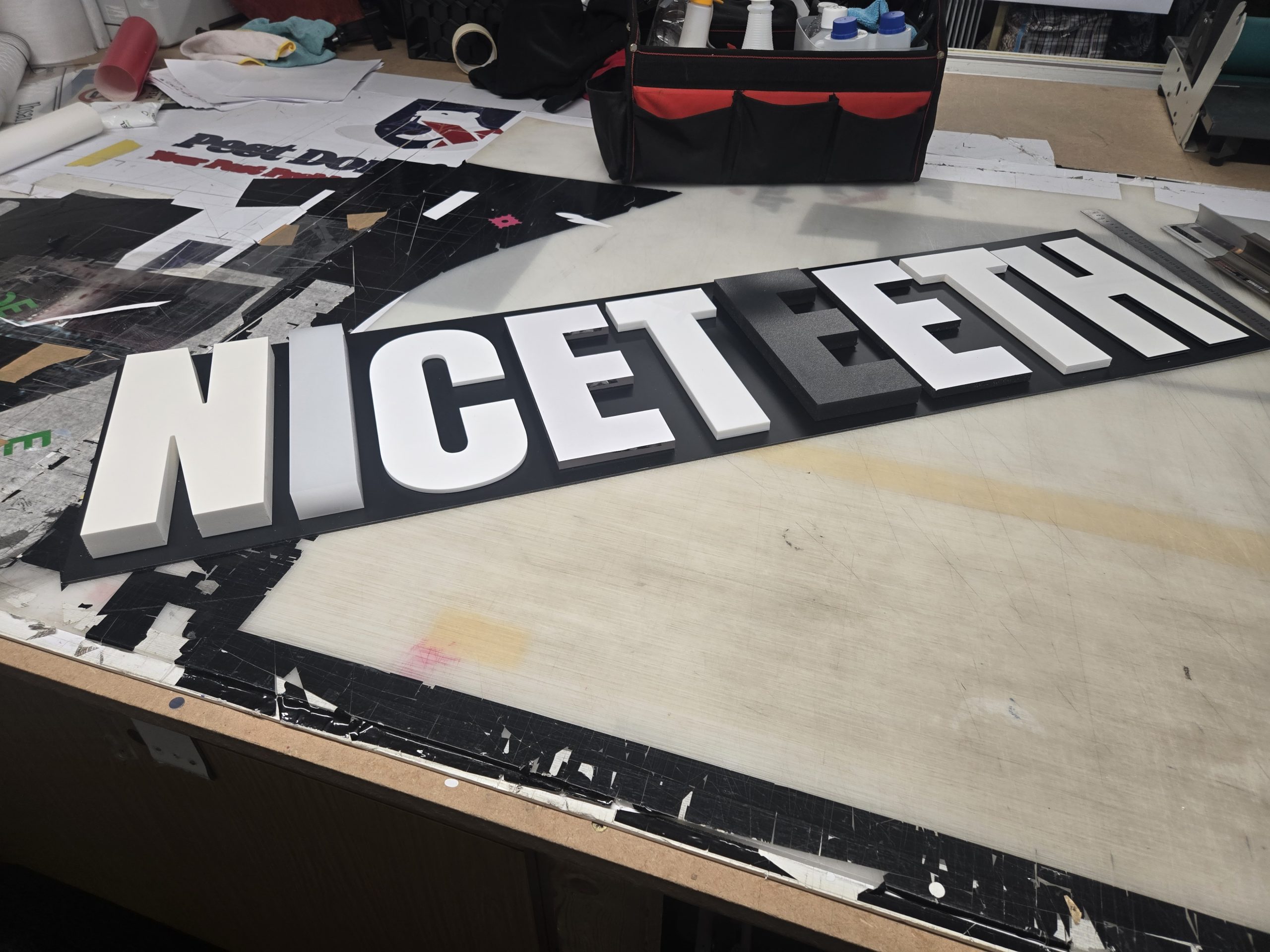 White Niceteeth dimensional lettering arranged on the workshop bench.