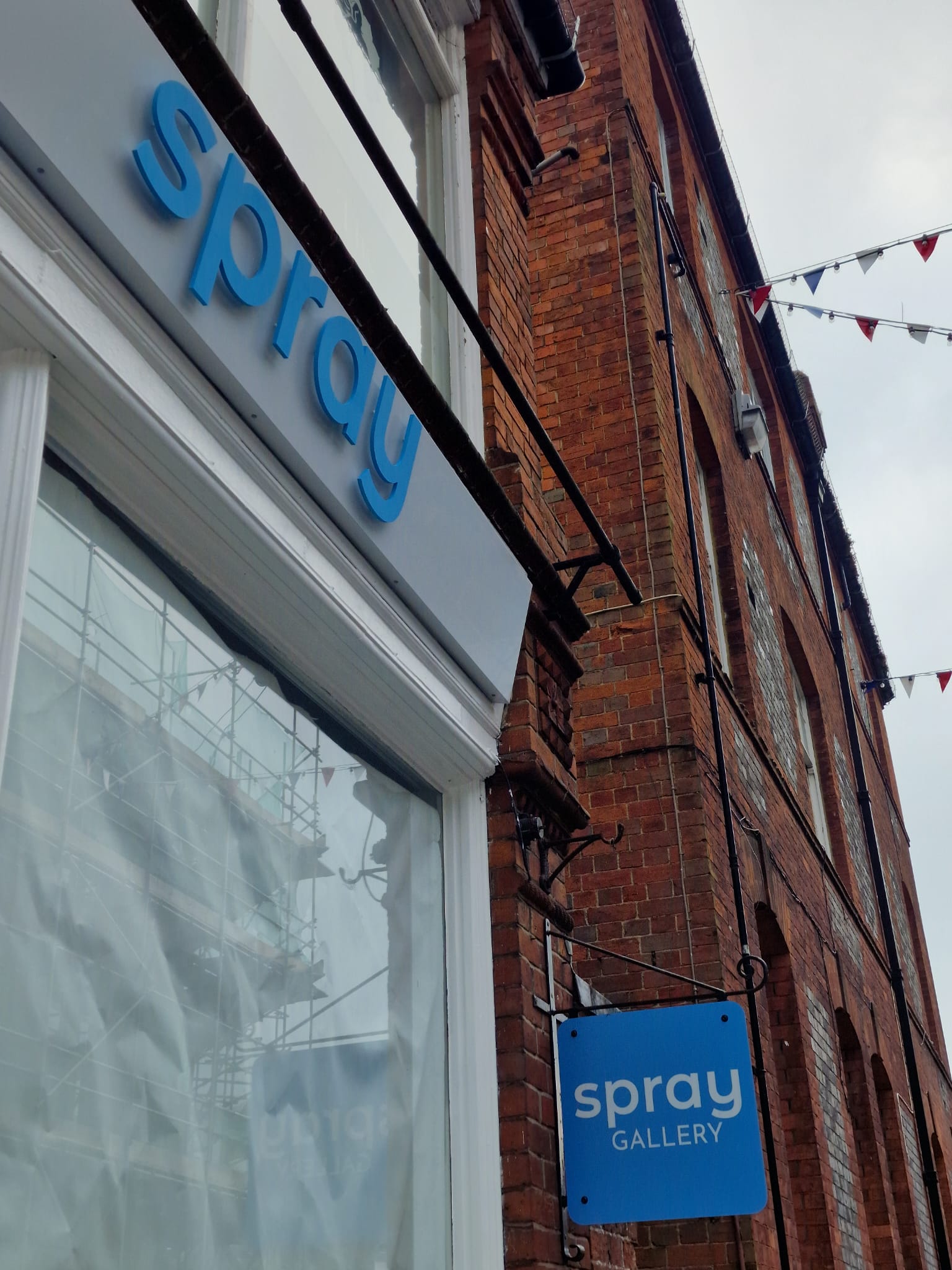 Custom blue Spray lettering mounted on the white gallery fascia.