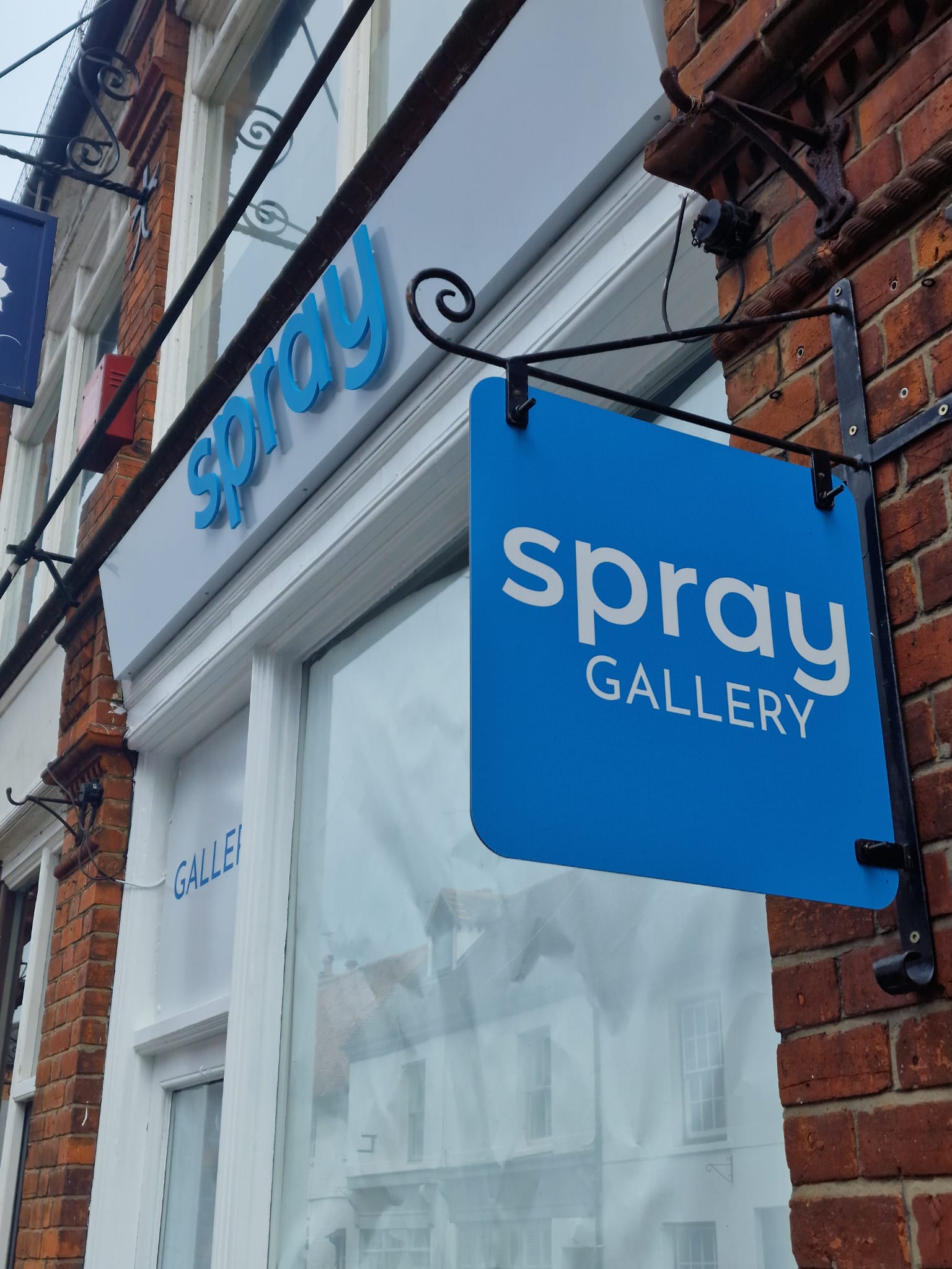 Blue Spray Gallery projecting sign and raised fascia lettering.